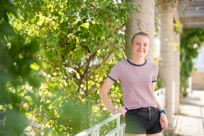 Uniformed Services and Sport student standing in front of greenery and smiling