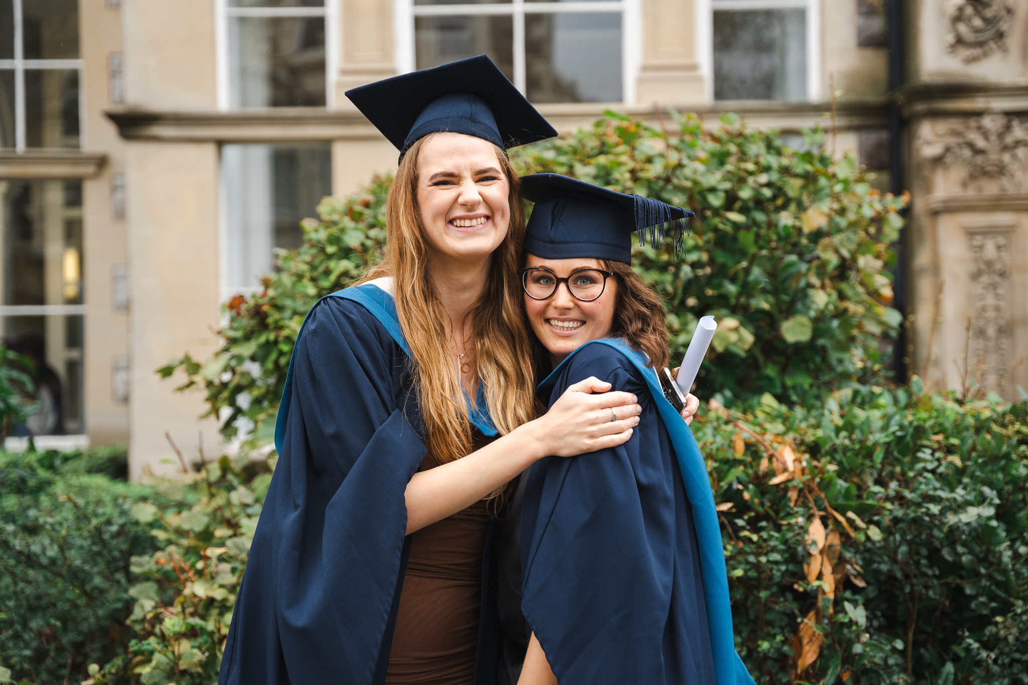 two female students embracing at graduation at university centre weston