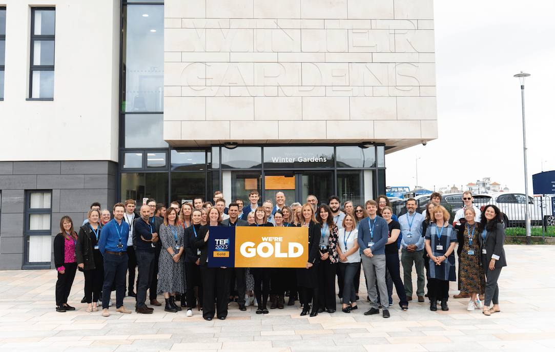 University staff holding TEF GOLD sign outside Winter Gardens campus