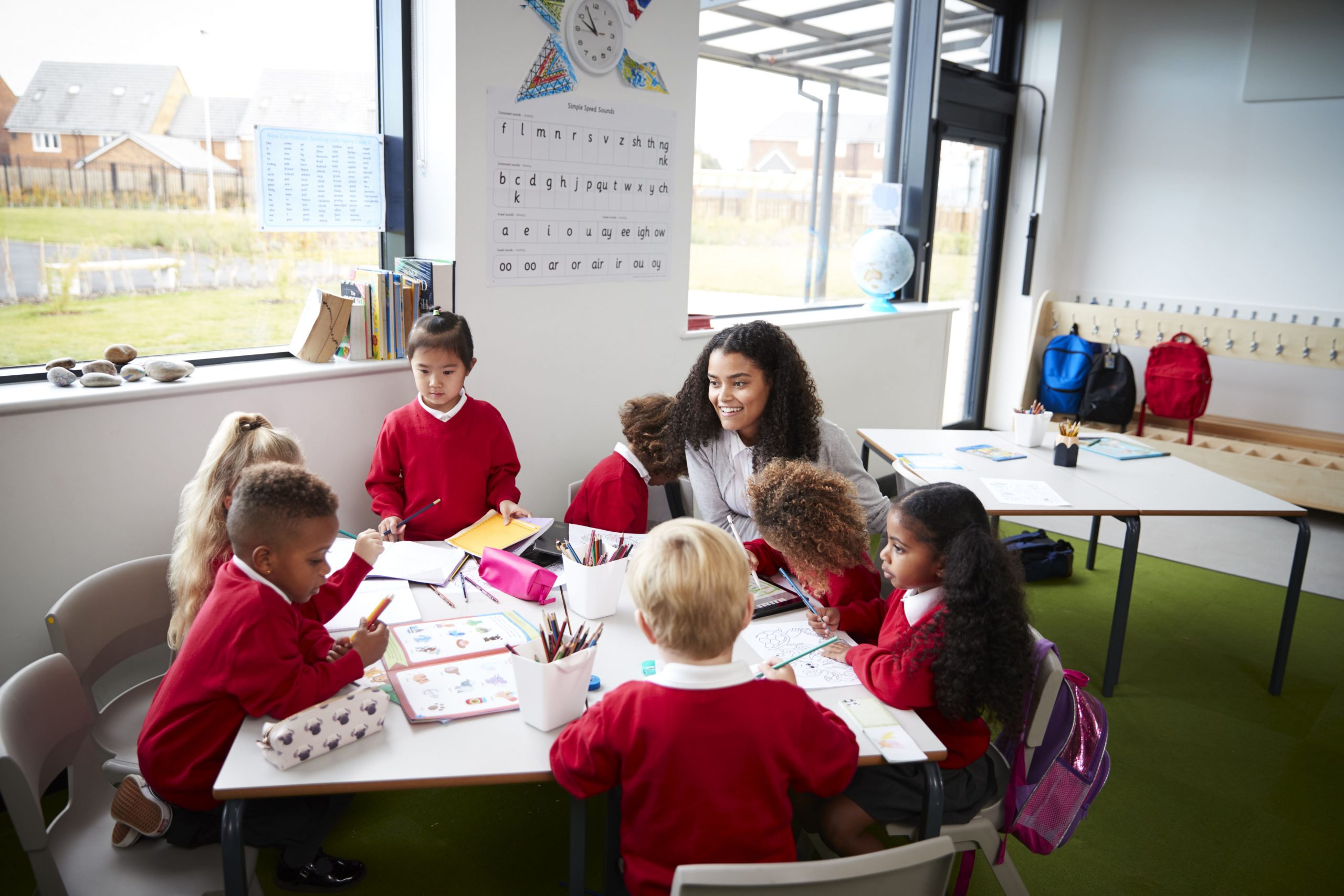 children learning around a table in a classroom with their teacher